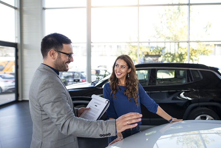 Car dealer presenting new car to the customer.